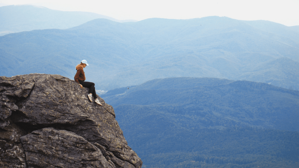 a person sitting at the edge of a cliff